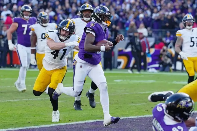 featured-image-1765384342254 Dec 7, 2025; Baltimore, Maryland, USA; Baltimore Ravens quarterback Lamar Jackson (8) runs with the ball for a touchdown against Pittsburgh Steelers linebacker Payton Wilson (41) during the first half at M&T Bank Stadium. Mandatory Credit: Mitch Stringer-Imagn Images