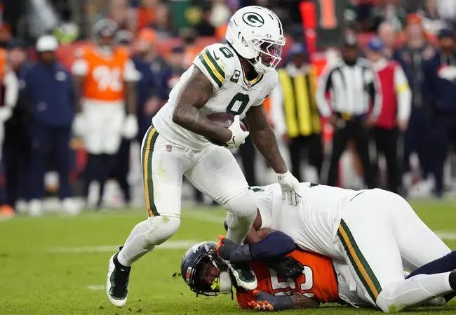 featured-image-1765901321890 Dec 14, 2025; Denver, Colorado, USA; Green Bay Packers running back Josh Jacobs (8) runs for a gain past Denver Broncos linebacker Nik Bonitto (15) during the third quarter at Empower Field at Mile High. Mandatory Credit: Ron Chenoy-Imagn Images