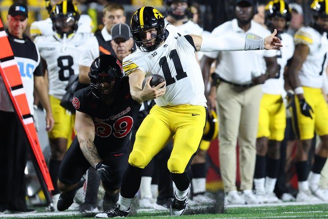 Sep 19, 2025; Piscataway, New Jersey, USA; Iowa Hawkeyes quarterback Mark Gronowski (11) is tackled by Rutgers Scarlet Knights defensive lineman Eric O'Neill (99) during the first half at SHI Stadium. Mandatory Credit: Vincent Carchietta-Imagn Images